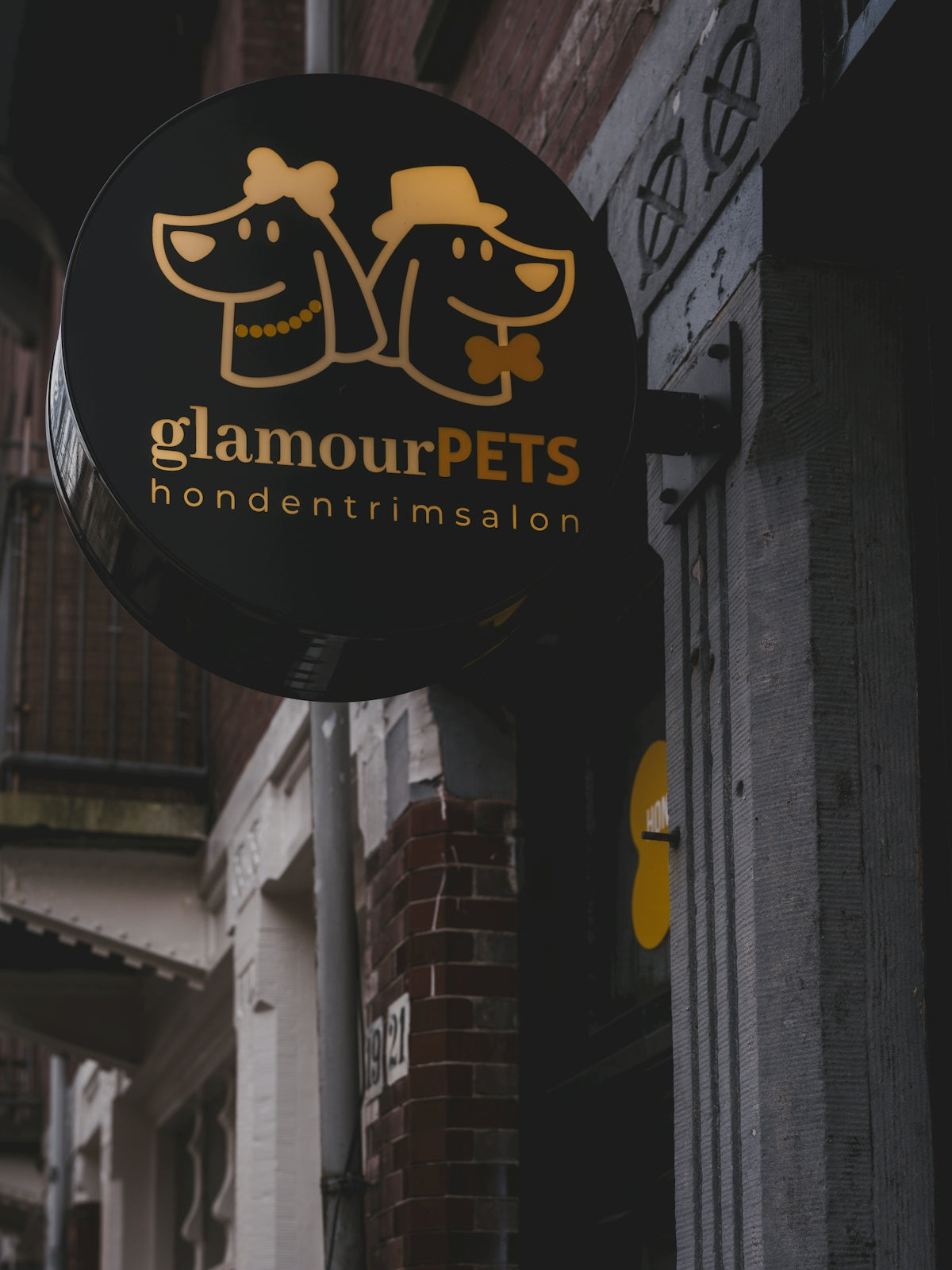 A round black glamourpets sign with two dog silhouettes.